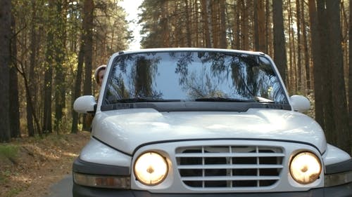 在森林中的狭窄道路上的白色越野车与照明大灯的慢动作镜头 · 免费素材视频