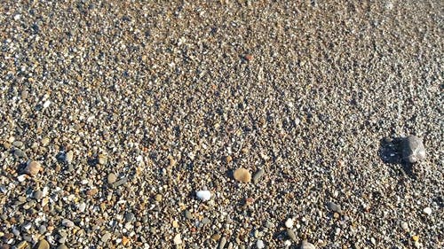 海浪将鹅卵石和小石头推到岸边 · 免费素材视频