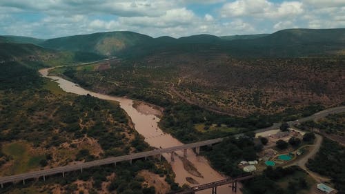 横跨群山环抱的河上桥梁的航拍画面 · 免费素材视频