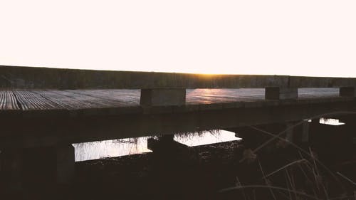 地平线与太阳落山的草原包围的一座木桥的特写镜头 · 免费素材视频