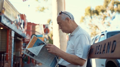 读报纸坐在板凳上的老人 · 免费素材视频
