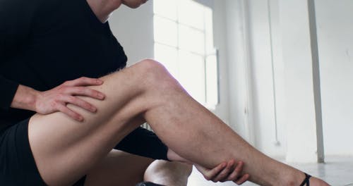 摩擦他的小腿的一个男性baller舞蹈家 · 免费素材视频