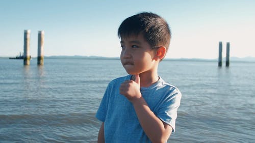在海滩上穿蓝色衬衫的可爱男孩 · 免费素材视频