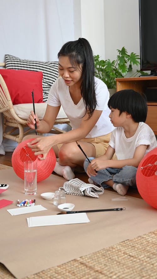一个女人和她的孩子在地板上画红灯笼 · 免费素材视频