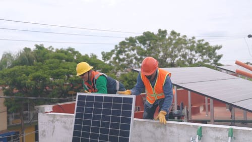 两名男子携带太阳能电池板进行安装 · 免费素材视频