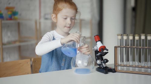 一个女孩一边把液体从佛罗伦萨烧瓶转移到气球一边说话 · 免费素材视频