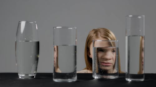 一个女孩的脸倒映在带水的水杯上 · 免费素材视频