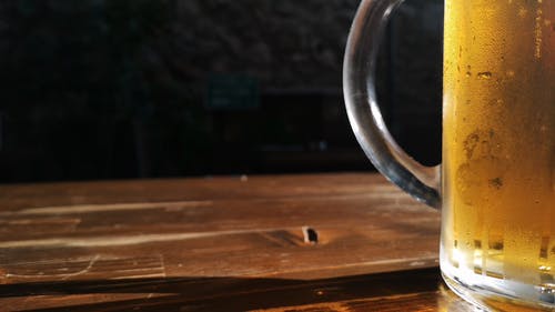 一个杯子在木桌顶部的冷的生啤酒 · 免费素材视频