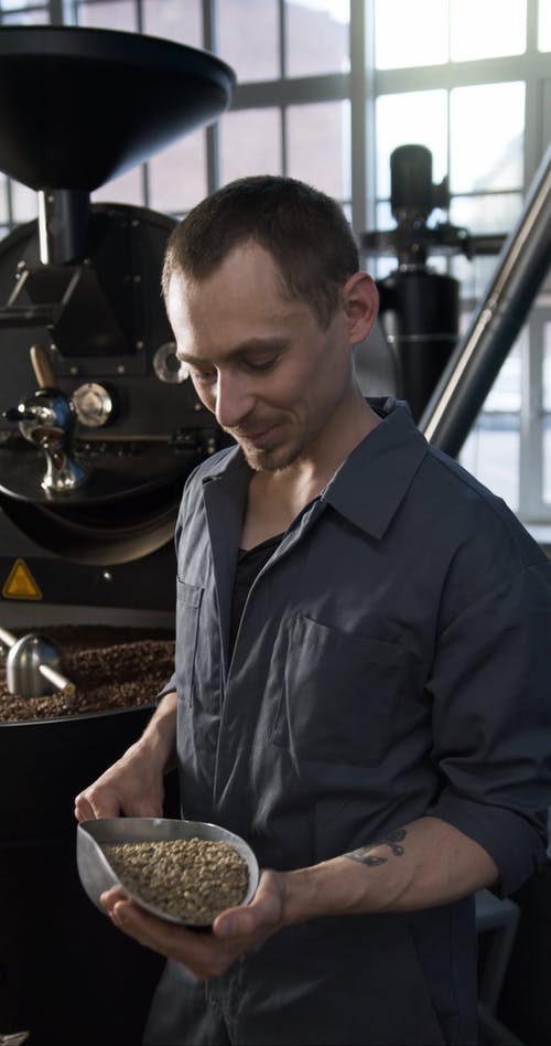 一个男人将生咖啡豆与成品进行比较 · 免费素材视频