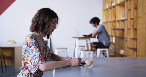 一个女人边喝咖啡边写笔记 · 免费素材视频