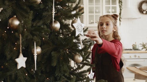 一个女孩忙着安排挂在圣诞树上的装饰品装饰 · 免费素材视频