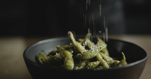 在碗中的煮熟的大豆豆荚上撒些盐 · 免费素材视频