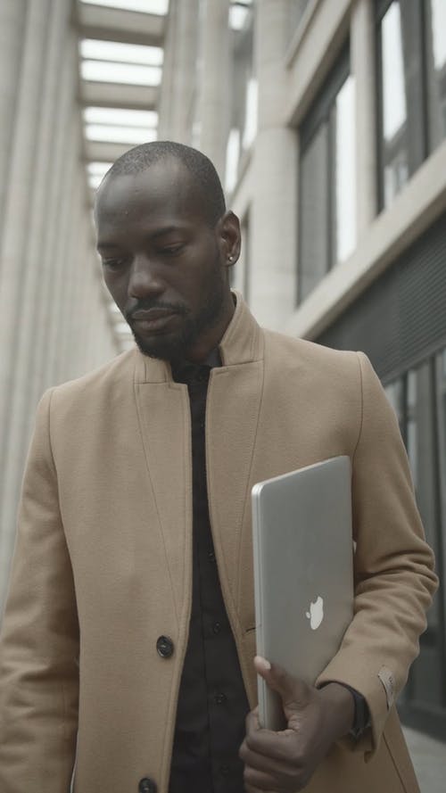 男人穿着大衣，拿着mac Book Pro · 免费素材视频