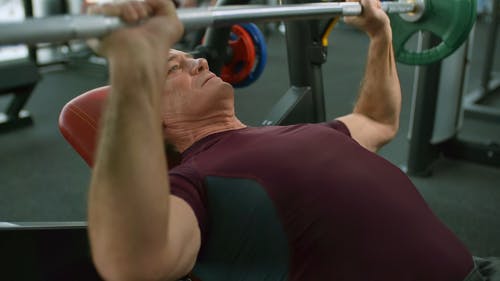 一个老人在健身房举重 · 免费素材视频