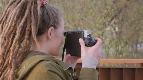 一个女人使用带有即时胶卷的现代相机拍摄一组照片 · 免费素材视频