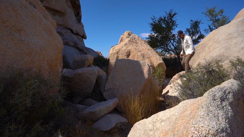 男子踩在岩石和巨石上穿越 · 免费素材视频