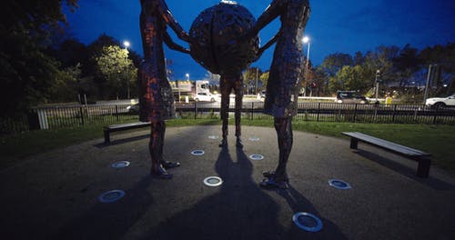 三个女人雕塑在公园举行一个地球仪 · 免费素材视频