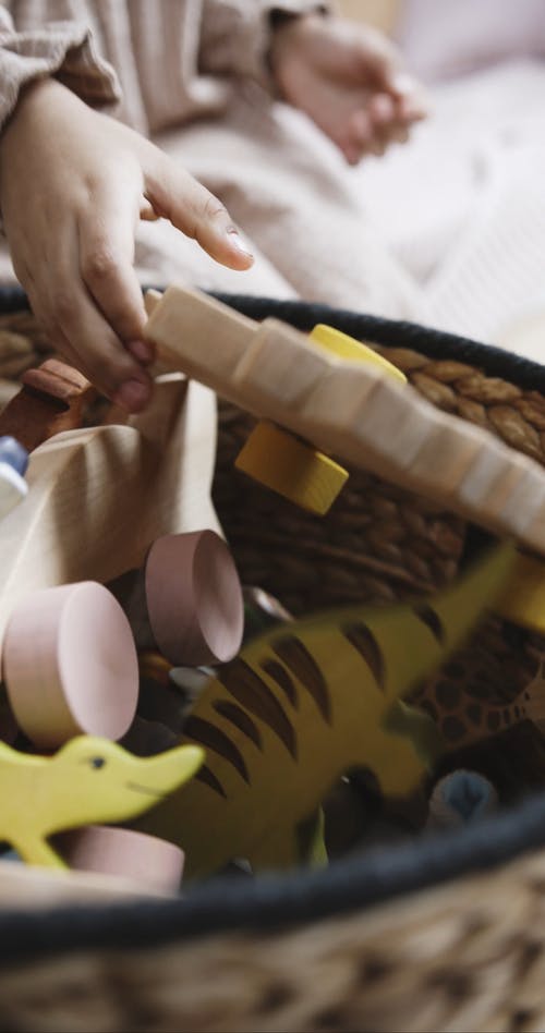 一个孩子正在选择放在玩具篮上的木制玩具 · 免费素材视频