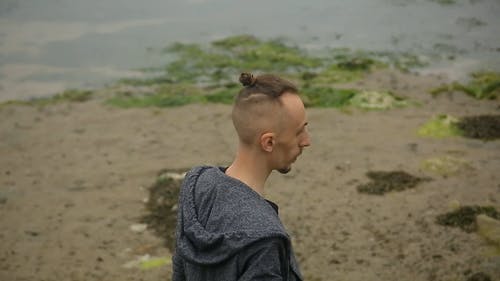 一个人站在湖边，在水上扔一块石头 · 免费素材视频