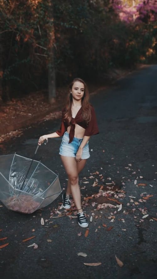 拍摄的女人举起一把伞与下降的干树叶的视觉效果 · 免费素材视频