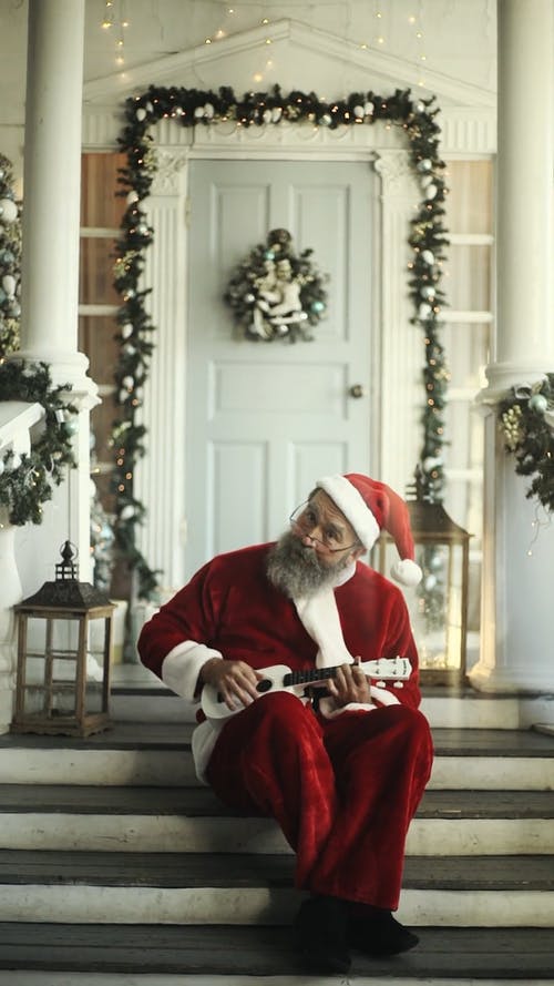 圣诞老人坐在门口的楼梯上玩ukelele · 免费素材视频