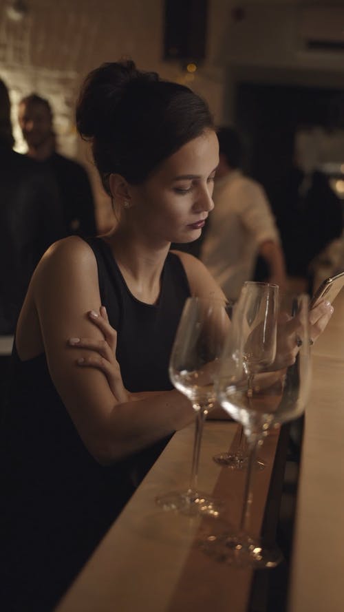 一个女人看着她的手机后离开酒吧 · 免费素材视频