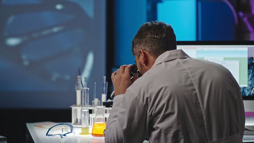 显微镜下的一个人研究样本并将其记录在计算机中 · 免费素材视频
