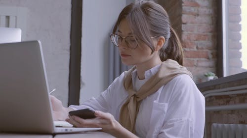 忙碌的女人，与她的笔记本电脑和智能手机一起工作 · 免费素材视频