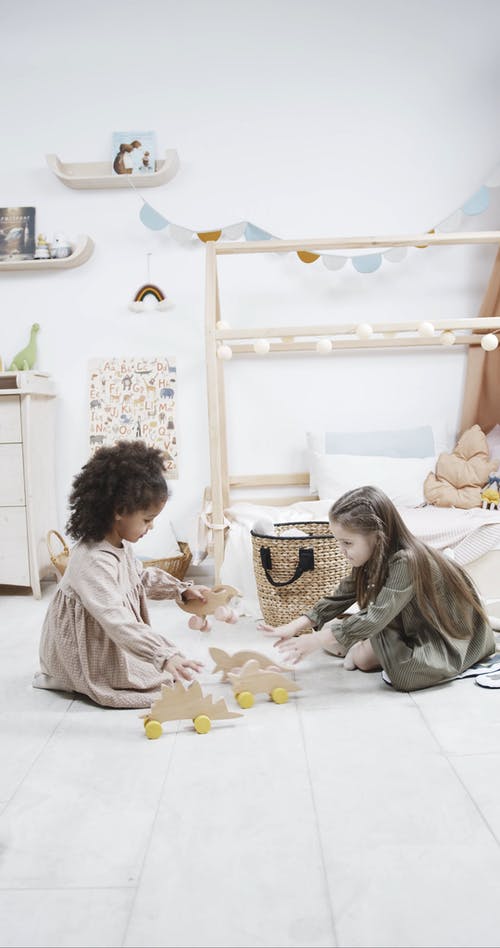 两个年轻女孩玩带轮子的木制恐龙玩具 · 免费素材视频