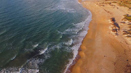 波浪亲吻海滩长海岸线的无人机画面 · 免费素材视频