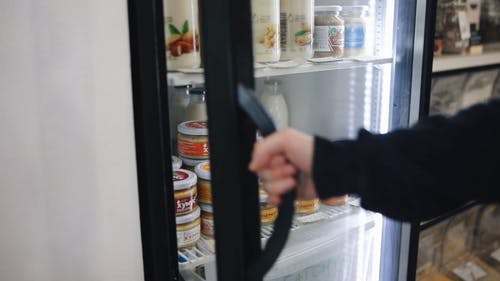 在杂货店的冰箱里拿食物的人 · 免费素材视频