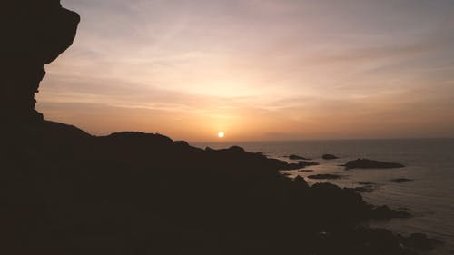 从多岩石的海岸线海地平线上的日落美景 · 免费素材视频