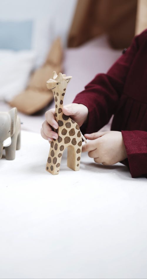 一个小女孩在玩木制长颈鹿玩具 · 免费素材视频