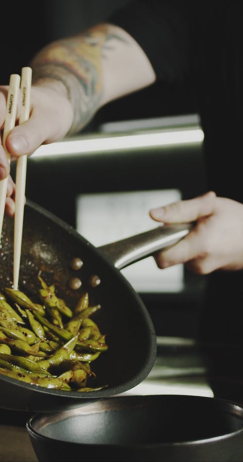 一个人在服务碗中转移煮熟的大豆荚 · 免费素材视频