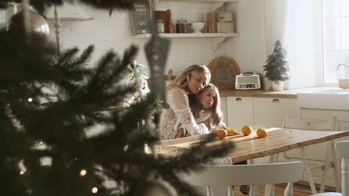 母亲和女儿在厨房里吃橙色水果 · 免费素材视频