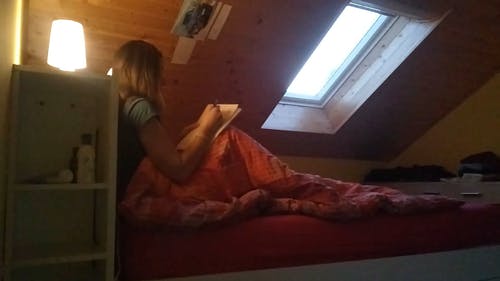 一个女人在床上写在用笔的笔记本上 · 免费素材视频