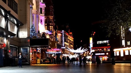 人们走在街上与圣诞节装饰品在晚上展出 · 免费素材视频