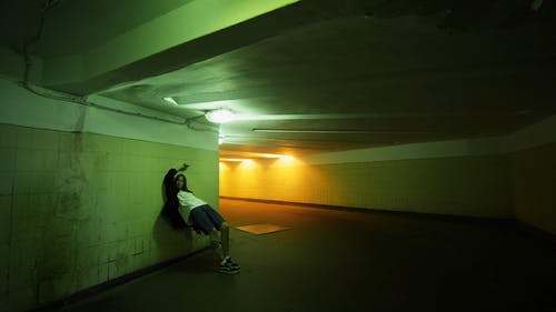一个女人斜倚在地下通道的墙上 · 免费素材视频