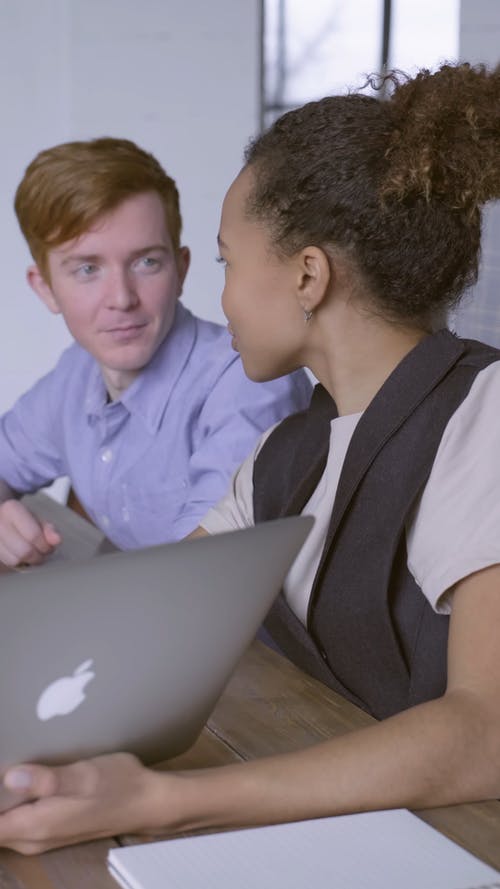 一个女人向使用笔记本电脑的男人讲解 · 免费素材视频