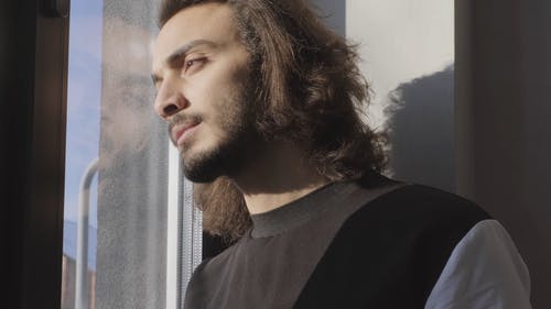 男子站在窗户与阳光透过他的脸 · 免费素材视频