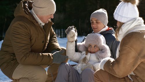 一个女孩和她的家人在雪地里闻到草杂草 · 免费素材视频