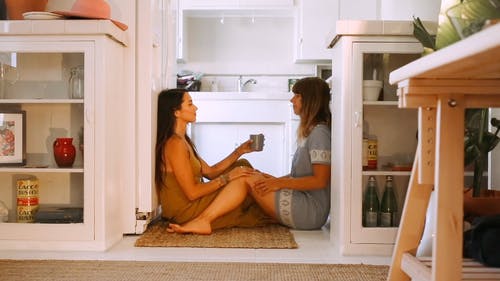 两个女人坐在厨房的地板上 · 免费素材视频