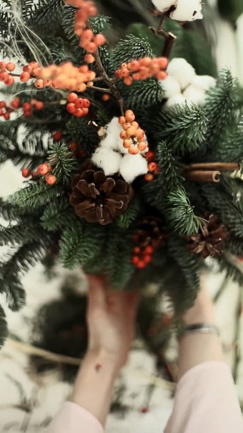 一个人把圣诞节装饰摆放在花瓶里 · 免费素材视频