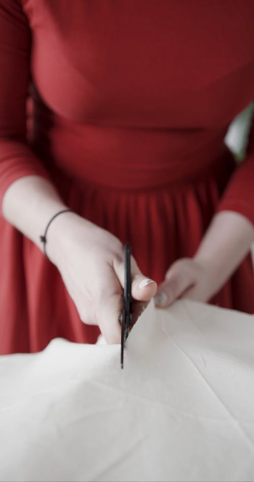 一个穿着红色衣服的人用剪刀剪面料 · 免费素材视频