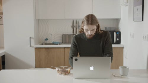 一个人在厨房里的笔记本电脑上工作时吃早餐 · 免费素材视频
