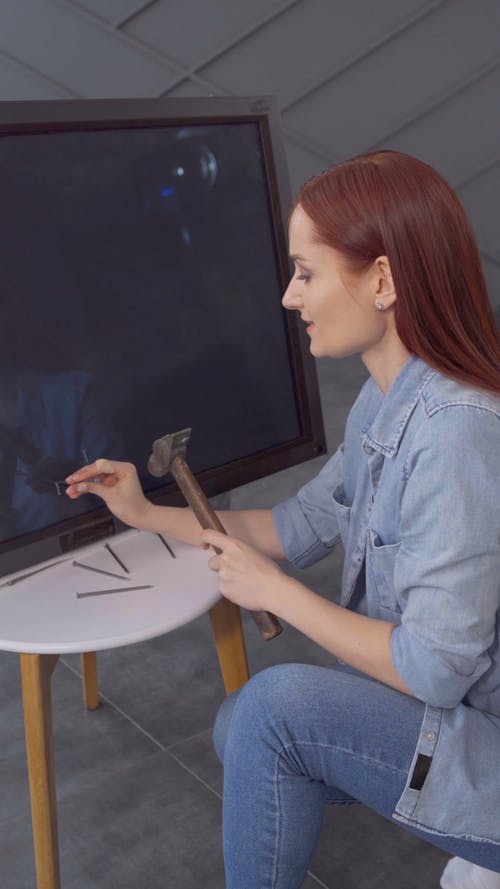 一个女人被锤子钉在屏幕上完全破坏了电视机 · 免费素材视频