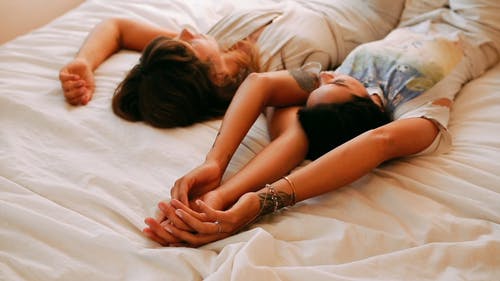 一对同性恋夫妇躺在床上，手牵着手 · 免费素材视频