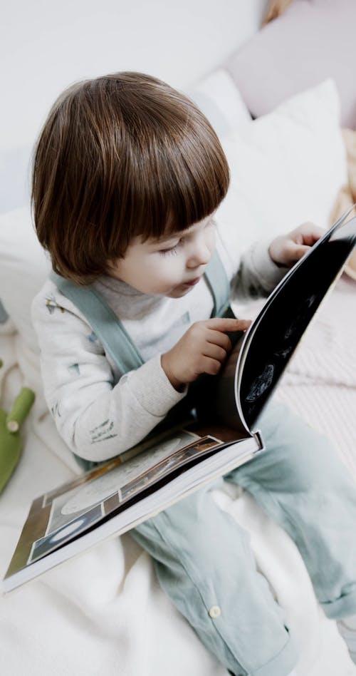 一个孩子看着一本书中的打印的图片 · 免费素材视频