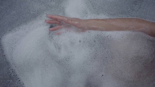 一个人在浴缸里洗澡时玩肥皂泡沫 · 免费素材视频