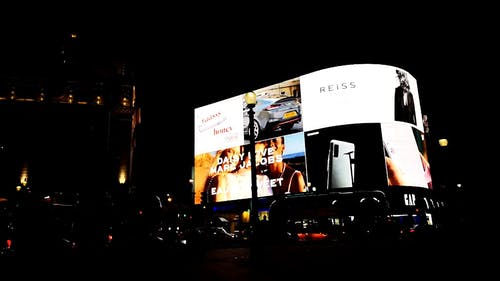 电子广告牌的巨型屏幕在晚上照亮伦敦的街道 · 免费素材视频